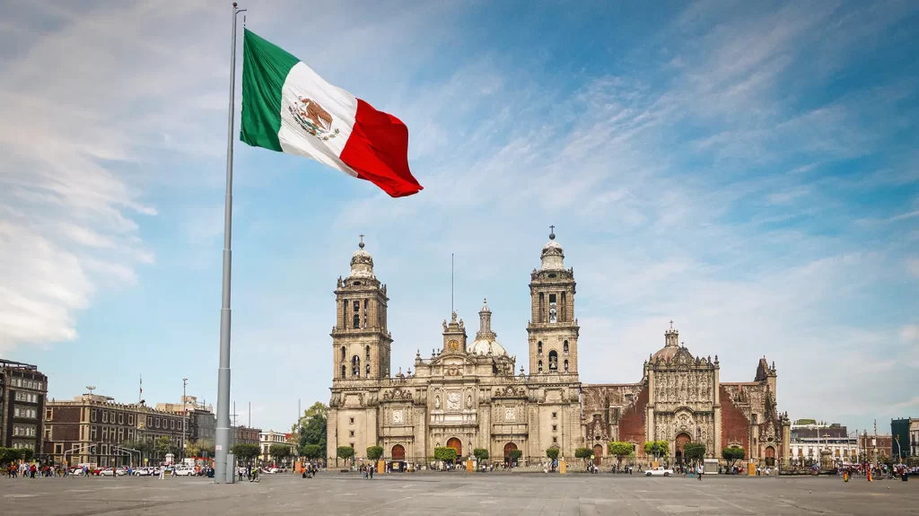 visual of ancient spanish church in the heart of mexico city with a mexican flag in the middle of the town square