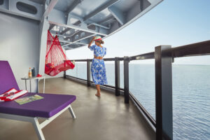 A Sailor walks to her Sailor Mate in the hammock on the large balcony of their Cheeky Corner suite.